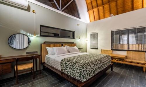 a bedroom with a bed and a desk and a mirror at Asri loka villa in Ubud