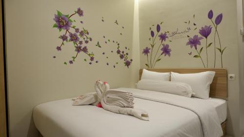 a bedroom with two beds with purple flowers on the wall at The One Residence Tanah Abang in Jakarta