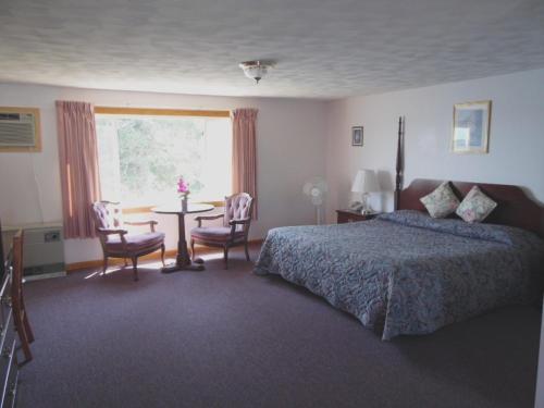 a bedroom with a bed and a table and a window at Redclyffe Shore Motor Inn in Robbinston