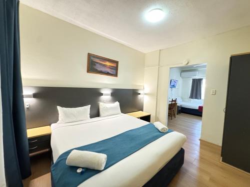 a bedroom with a large white bed with a blue blanket at Taree Motor Inn in Taree