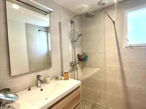 a bathroom with a sink and a shower with a mirror at Charmante maison à Groix proche du port - FR-1-813-35 in Kerlo