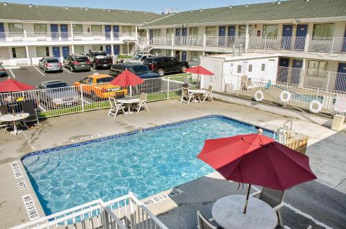 a swimming pool with a red umbrella and tables and chairs at Motel 6-Tacoma, WA - South in Tacoma