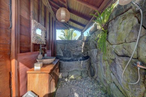 a bathroom with a stone wall and a sink at Gedong Batu Villas in Ubud