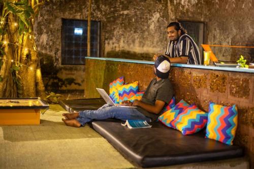 two men sitting on a bench with a laptop at goSTOPS Lite Alleppey in Alleppey