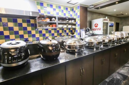 una fila de ollas y sartenes en una encimera en una cocina en Modern Business Hotel, en Gumi