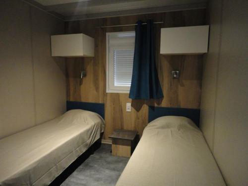 deux lits dans une petite pièce avec une fenêtre dans l'établissement Chalet neuf avec piscine couverte, proche mer, calme et sécurisé - 6 personnes - FR-1-777-8, à La Parée Preneau