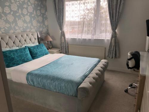 a bedroom with a bed with blue pillows and a window at Quaint and Peaceful - Calne in Calne