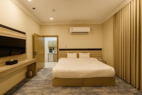 Un dormitorio con una cama y un televisor de pantalla plana. en فندق تلاق للخدمات الفندقيه, en Medina