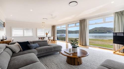 a living room with a couch and a table at Waterfront, Renovated, Walk To Ettalong in Pretty Beach