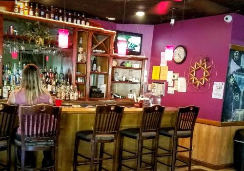 a woman sitting at a bar in a restaurant at Baymont by Wyndham Midland Airport in Midland
