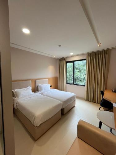 a hotel room with two beds and a window at Nirvana Nest - Corporate Stay, Gomti Nagar, Lucknow in Lucknow