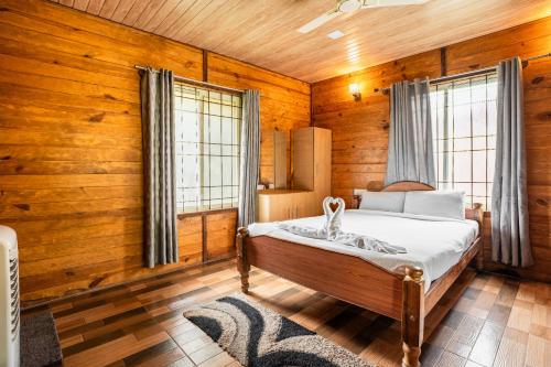 a bedroom with a bed in a room with wooden walls at Streamedge Sakleshpur in Hanbalu
