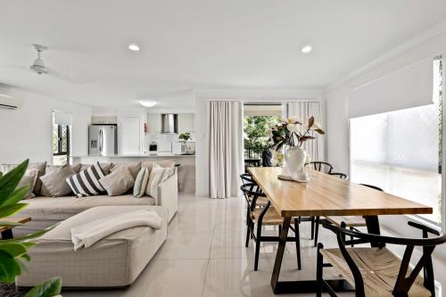 a white living room with a couch and a table at Beach Breeze Holiday House in Mackay