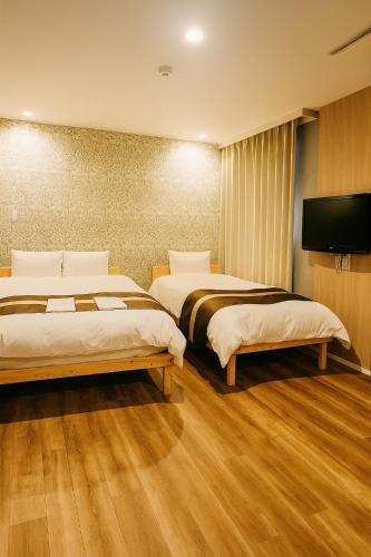 a hotel room with two beds and a flat screen tv at Beppu onsen Resort Stay Spa Tsurumi in Beppu