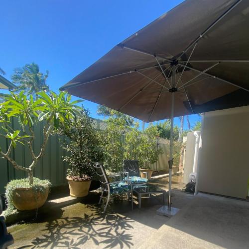 a patio with an umbrella and a table and chairs at Allawah at Wamberal in Wamberal