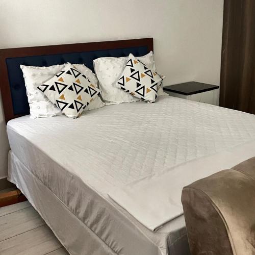 a bed with white sheets and pillows on it at Modern Smart Apartment with Easy Access in Mtwapa