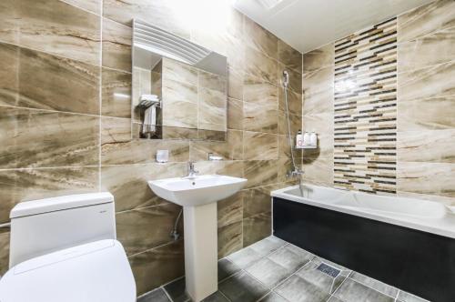 a bathroom with a toilet and a sink and a tub at Modern Business Hotel in Gumi
