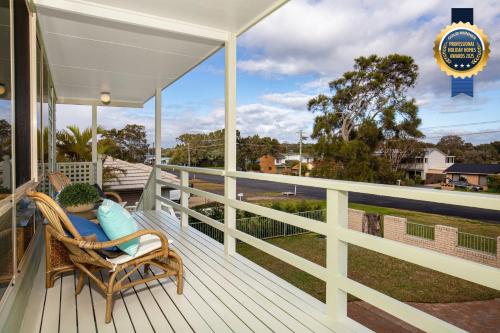 a woman sitting in a wicker chair on a porch at Palms I Pet Friendly I 2 Mins to Beach in Culburra Beach