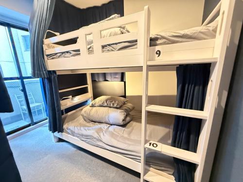 a bedroom with bunk beds with a bed in it at Wabi Sabi Hostel Shinjuku West in Tokyo