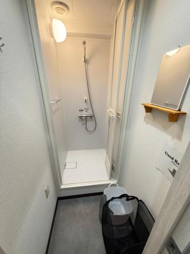 a small bathroom with a shower and a toilet at Wabi Sabi Hostel Shinjuku West in Tokyo