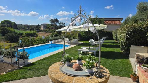 a garden with a swimming pool and an umbrella at Villa Malvasio Pool and Jacuzzi Room Sassari in Sassari