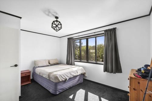 a bedroom with a bed and a window at Pakawau Inlet House in Pakawau
