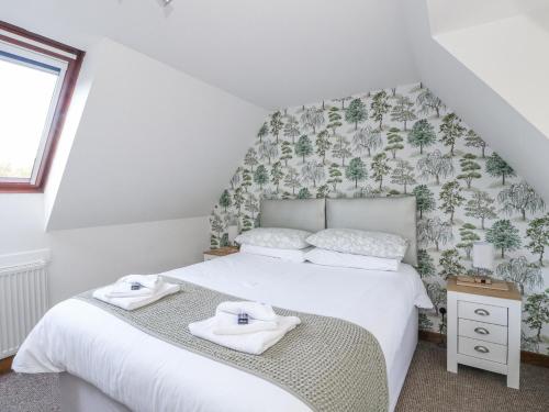a bedroom with a bed with two towels on it at Deskford Cottage in Balblair