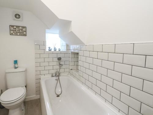 a white bathroom with a toilet and a bath tub at Deskford Cottage in Balblair