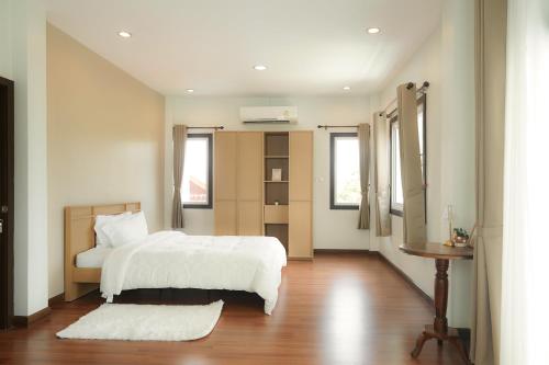 a bedroom with a white bed and a wooden floor at Browny house - Doi Suthep View in Chiang Mai
