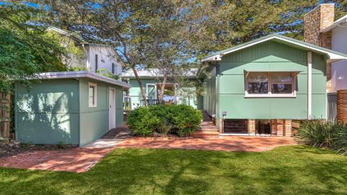 ein grünes Haus mit Garage im Hof in der Unterkunft Brisk Bay Cottage By Holidayco in Patonga