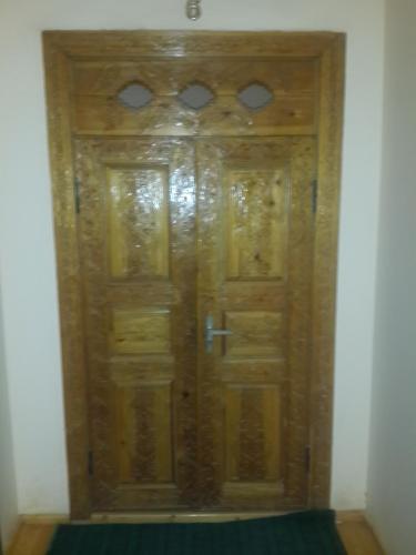 a wooden door in a room with a green rug at Islambek Hotel & Travel in Khiva