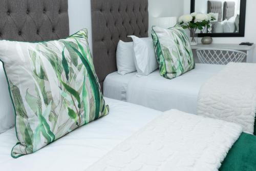 two white beds with green and white pillows at Relmies Place in Modimolle