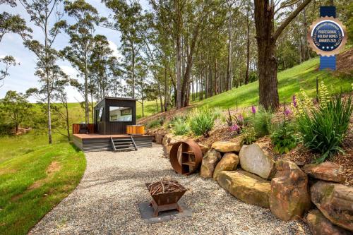 a visitor center in a garden with a bench and flowers at Burroo at Kangaroo Valley I Perfect Views I Outdoor Bath in Barrengarry