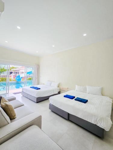 two beds in a white room with a couch at Khunnapat Pool Villa Pranburi in Ban Huai Thalaeng Phan