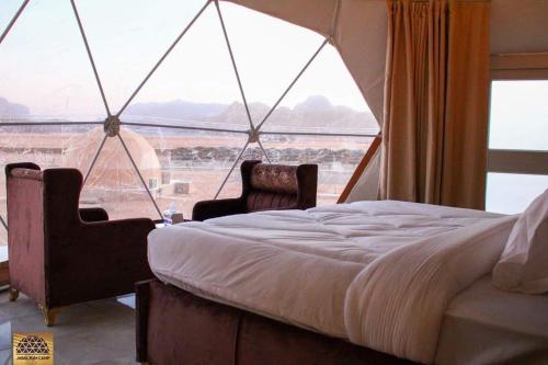 a bedroom with a bed and a large window at Wadi Rum in Al Jafr