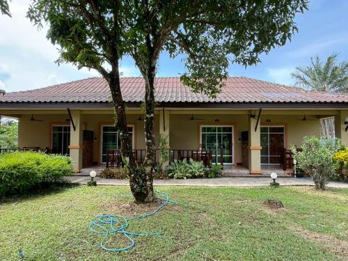 a yellow house with a tree in the yard at Sweet Mango Khaolak in Khao Lak