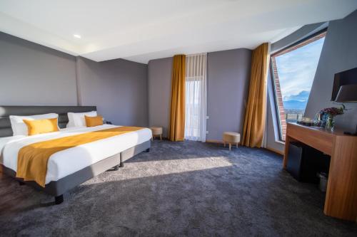 a hotel room with a bed and a large window at Burki Castle & Cellar in Kvareli