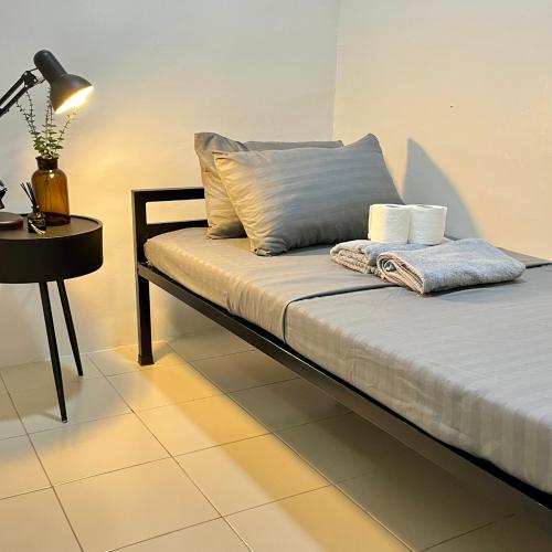 a bed in a room with a lamp and a table at Cozy 2 Bedroom Home in Lucena with AC and Fast WiFi in Ilayang Dupay