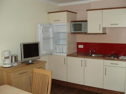 a kitchen with white cabinets and a computer on a desk at smartFLATS in Dorfgastein