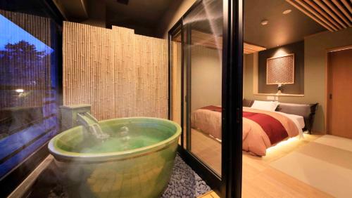 a bathroom with a tub in a bedroom with a bed at Hakone Fuga - Adult Only in Hakone