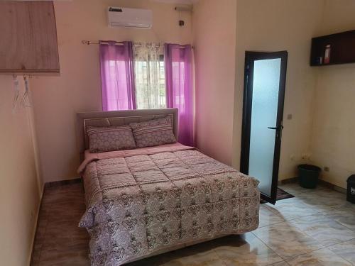 a bedroom with a bed in a room with pink curtains at Très Bel Appartement Moderne-1 Appartement Nuptial in Libreville