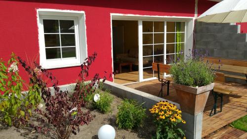 a red house with a wooden deck with flowers at Bungalows am Grimnitzsee in Joachimsthal