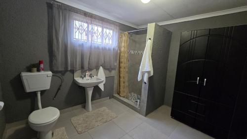 a bathroom with a toilet and a sink and a shower at Akwaaba Fie Guesthouse in Lebowakgomo