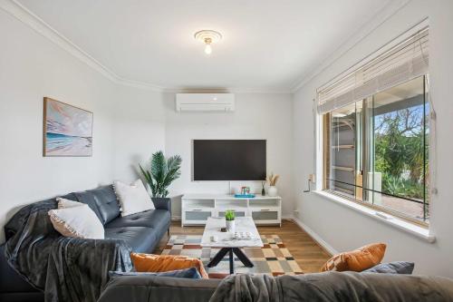 a living room with a couch and a tv at Seaview Escape Ocean Views & 500MBs Wifi in Perth