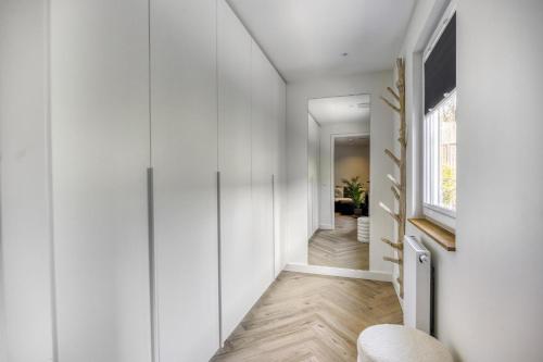 Un pasillo con paredes blancas y una puerta con ventana. en Cosy Nest, en Noordwijk aan Zee