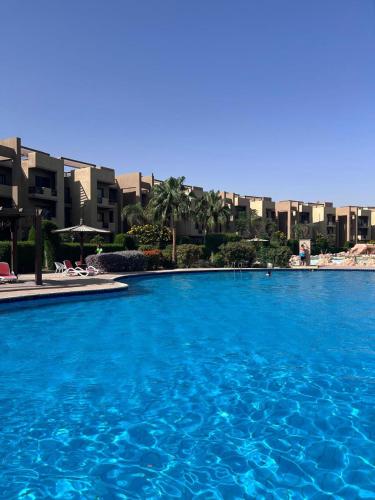 ein großer blauer Pool mit Gebäuden im Hintergrund in der Unterkunft قريه مرسيليا بلوباي السخنه --للعائلات فقط-Marseilia Blue Bay Ain Sokhna Village-- families only-- in Ain Suchna