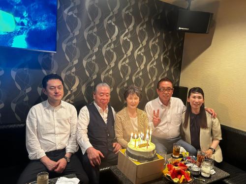 a group of people sitting around a cake with candles at Hotel Sun tsuyama in Tuyama