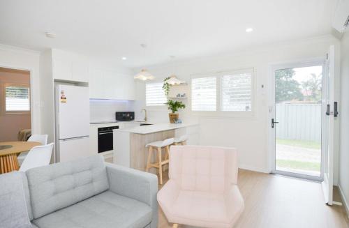 a kitchen and living room with a couch and chairs at Haven at Redcliffe - your stay on the Peninsula in Redcliffe