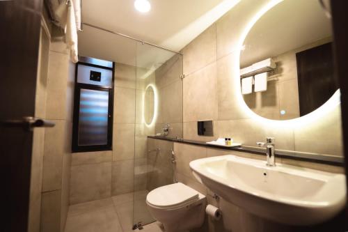 a bathroom with a sink and a toilet and a mirror at SinQ Village in Bambolim