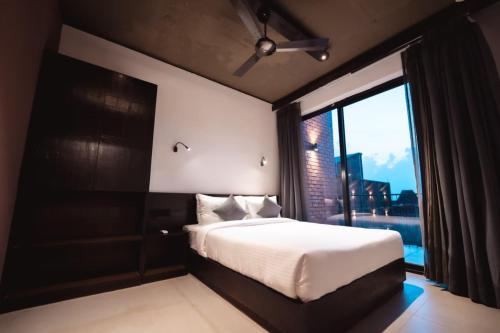 a bedroom with a bed and a large window at SinQ Village in Bambolim